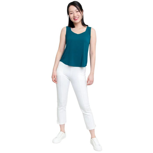 female model wearing teal green ritzy tank top and white nadine cropped pants front view on white background