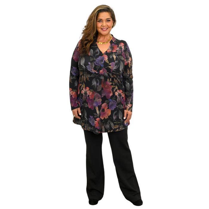 a woman wearing pink petal print edwina tunic top and black daya pants front view set on a studio white background