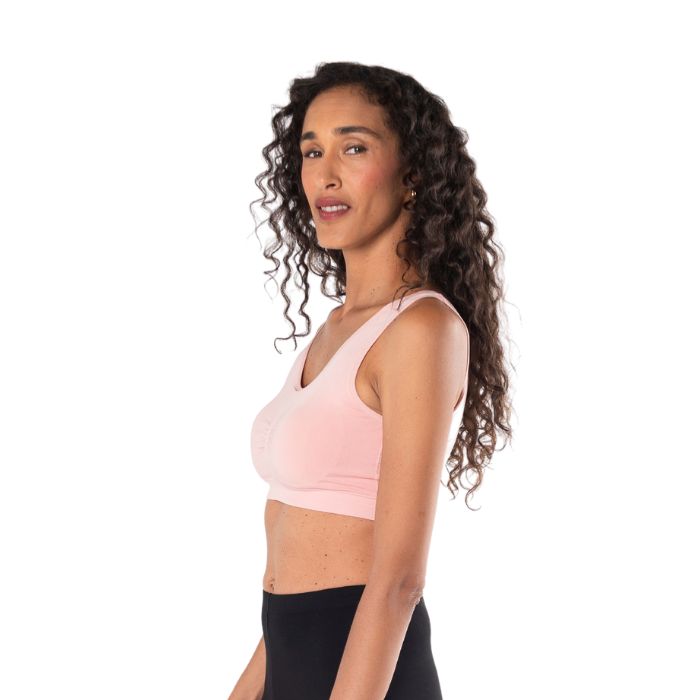 female model wearing pink essential bralette side view on white background
