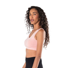 top of female model wearing pink essential bralette side view on white background