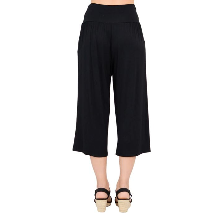 female model wearing black gaylene capri pants back view on white background