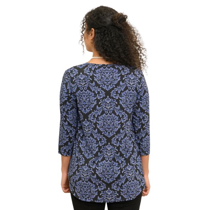 a woman wearing indigo empire print jazz top waist up back view on white backgrouna