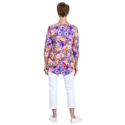 female model wearing jazz violet fiesta print three quarter sleeve top and white nadine cropped pants back view on white background