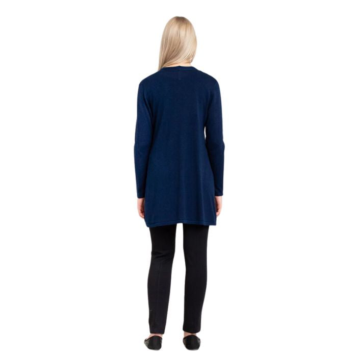 female model wearing indigo blue justine draped cardigan sweater and nlack nadia pants back view on white background