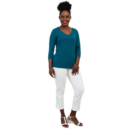 female model wearing mia teal green three quarter sleeve top and nadine white cropped pants front view on white background