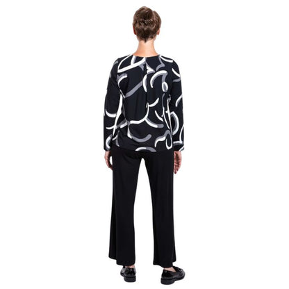 woman wearing black white focus print peggy top and black parker pants back view set on a white background