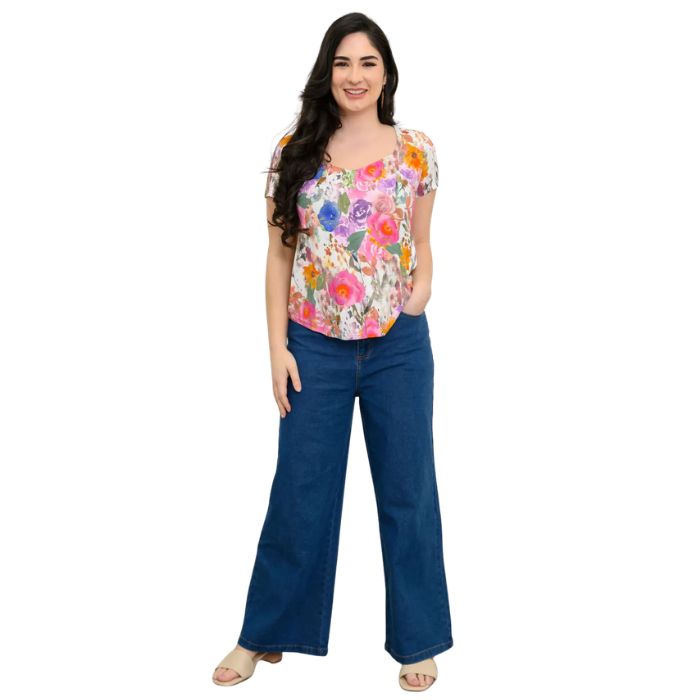 female model wearing pink bouquet print ritzy top and denim blue jeans front view on white background