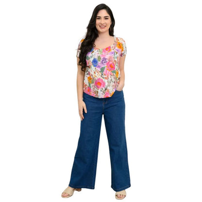 female model wearing pink bouquet print ritzy top and denim blue jeans front view on white background