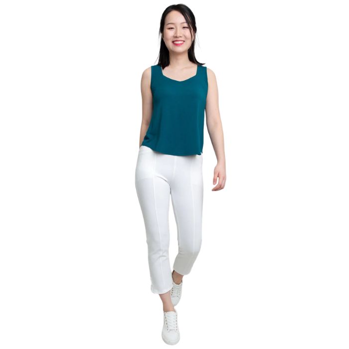 female model wearing teal green ritzy tank top and white nadine cropped pants front view on white background