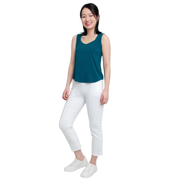 female model wearing teal green ritzy tank top and white nadine cropped pants front view on white background