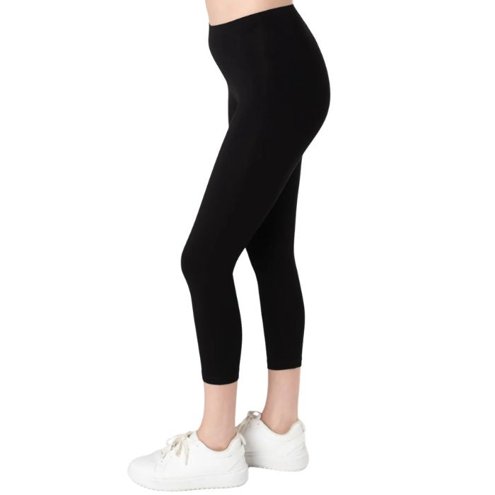 female model wearing black suri capri length leggings side view on white background