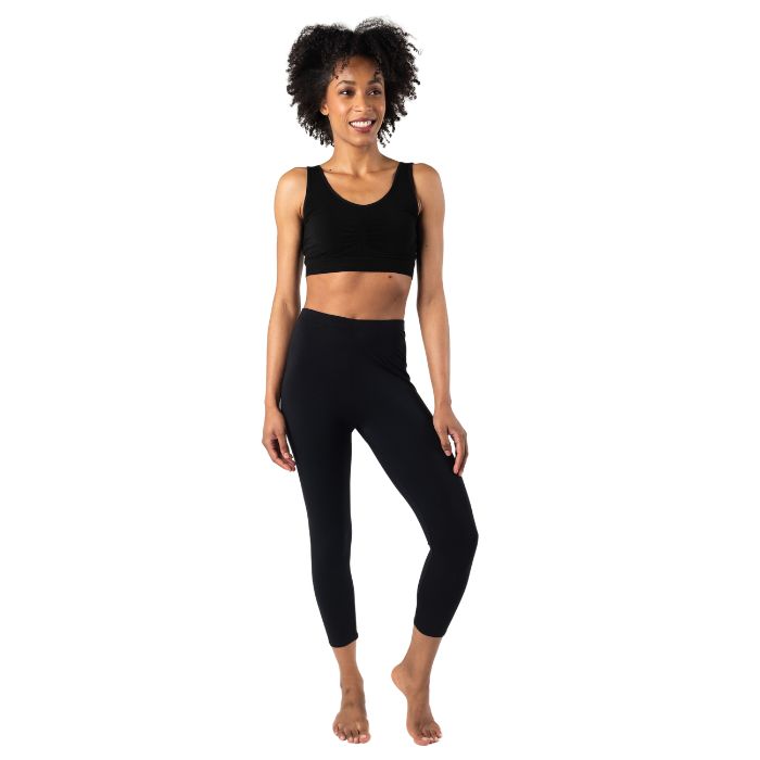 female model wearing black suri capri length leggings and black terrera essential bralette front view on white background 