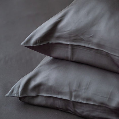 two charcoal grey terrera bamboo pillowcases on pillows stacked on grey background