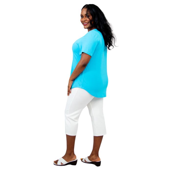 female model wearing turquoise blue tessa tee and white nadine cropped pants side view on white background